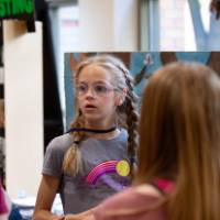 student standing at a composting poster talking to attendees at student project showcase
